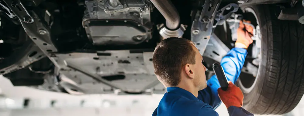 Mechanic inspecting a vehicle's undercarriage